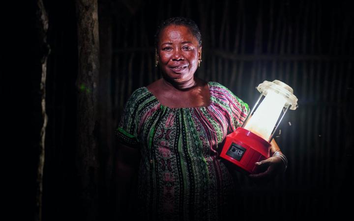Portrait de Kingeline, une ingénieure en énergie solaire, tenant une lampe solaire.